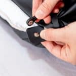 Hands fastening a black press stud on an Earthing Pillow Cover.