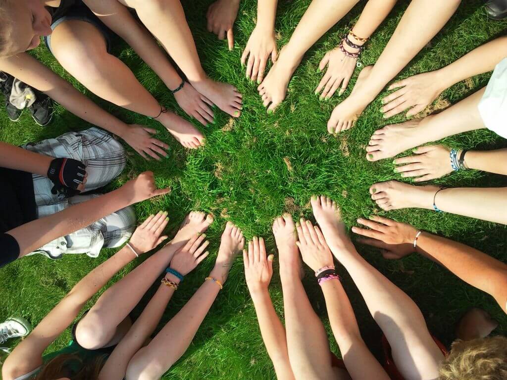 Group of People Barefoot on Grass in a Circle