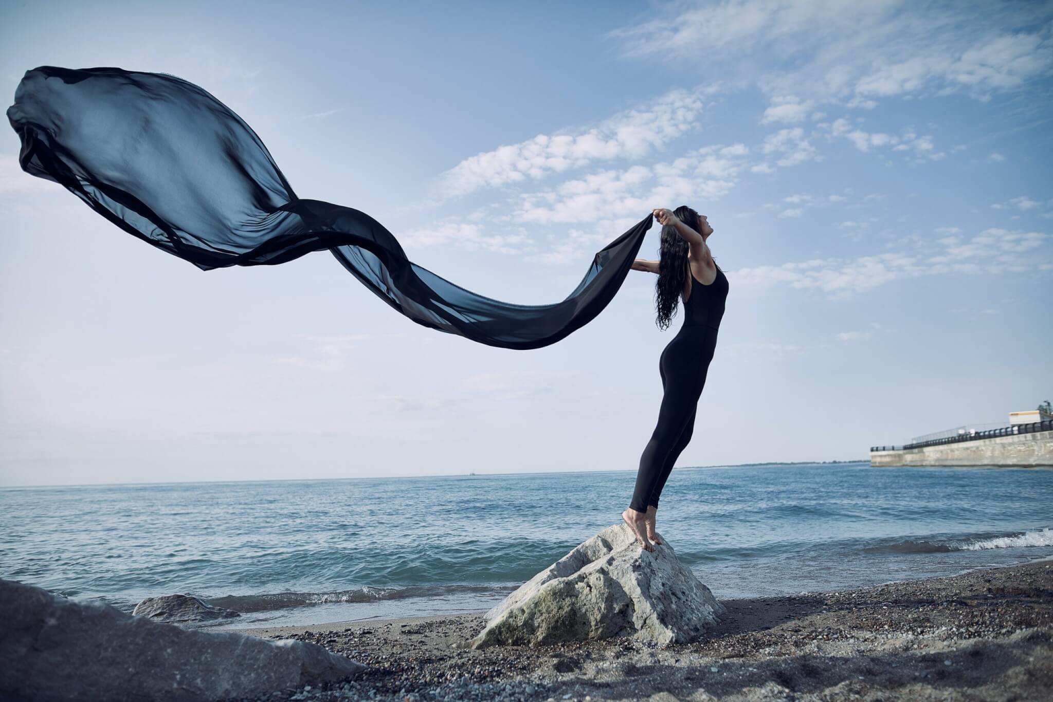 Woman Stretching Bare Foot on Rock at Beach