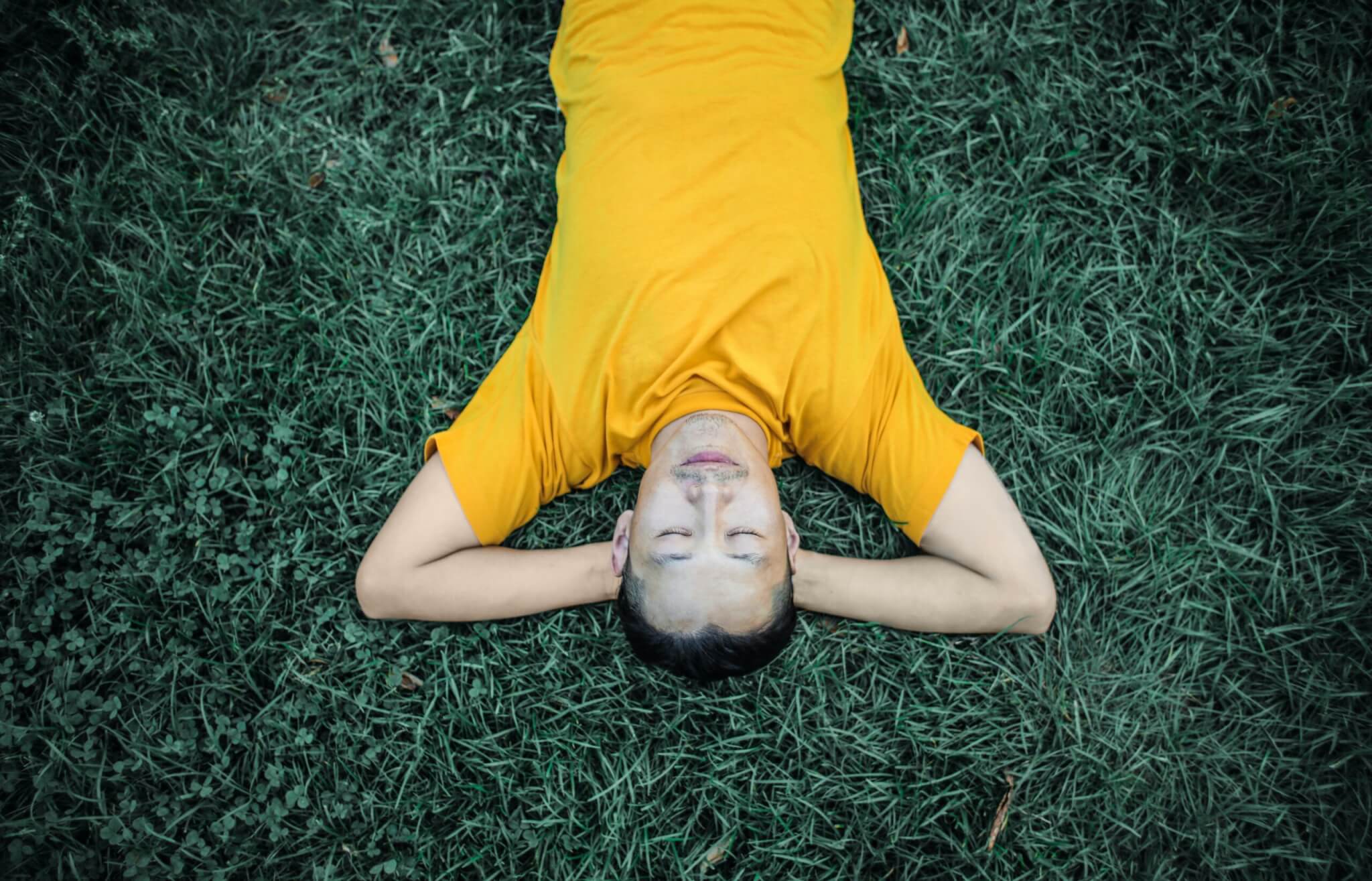 Man Wearing Yellow Lying Down on Grass