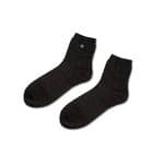 A pair of Grounding Socks in black, featuring a small round tag on the side of one sock, displayed on a plain white background.