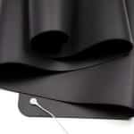 A close-up of the Grounders Yoga Mat, a large, flat black mat with smooth rolled edges. A white cord with a round connector is attached to one corner, indicating it’s an electronic grounding mat.
