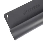 A partially unrolled dark grey Grounders Yoga Mat displays its embossed name on the surface, with a white cord attached to one corner.