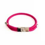 The Earthband PEMF Bracelet is a pink elastic bracelet with a silver clasp engraved with a leaf design, showcased on a white background.