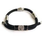 The EarthBand PEMF Bracelet by BeGrounded is a black cord bracelet with silver accents, featuring a central tree design, multiple silver connectors, and a magnetic clasp against a white background.
