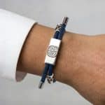 Earthband PEMF Bracelet in blue on a wrist, featuring a rectangular silver plaque with an embossed tree design and silver accents.