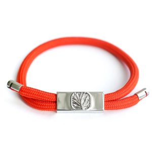 The EarthBand PEMF Bracelet from BeGrounded is a bright red braided accessory with silver clasps and a rectangular silver charm featuring an engraved feather design. Combining elegance and wellness, this therapeutic bracelet is infused with PEMF technology and set against a white background.