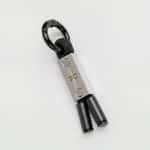 The Earthband For Pets is a modern PEMF keyring with a rectangular metal piece, minimalist design, black rope looped through it, two black cylindrical ends, and a black metal keyring.