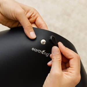 Hands attaching a snap connector to a black Earthing mat.