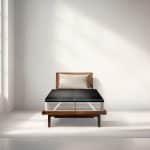 A mattress on a wooden bed frame with a black heating or cooling pad topper attached to the top.