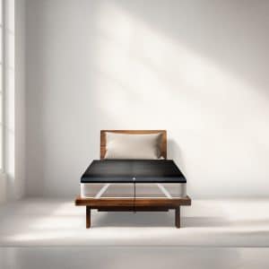 A mattress on a wooden bed frame with a black heating or cooling pad topper attached to the top.