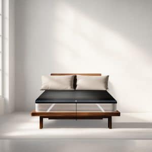 A black mattress topper with a power lead resting on a bed frame with two pillows.